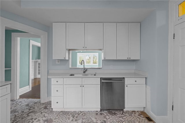 kitchen with a sink, light countertops, white cabinetry, baseboards, and stainless steel dishwasher