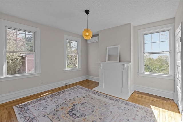 unfurnished dining area with an AC wall unit, baseboards, and a healthy amount of sunlight