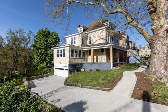 view of front of house with a front lawn, an attached garage, a chimney, a porch, and driveway
