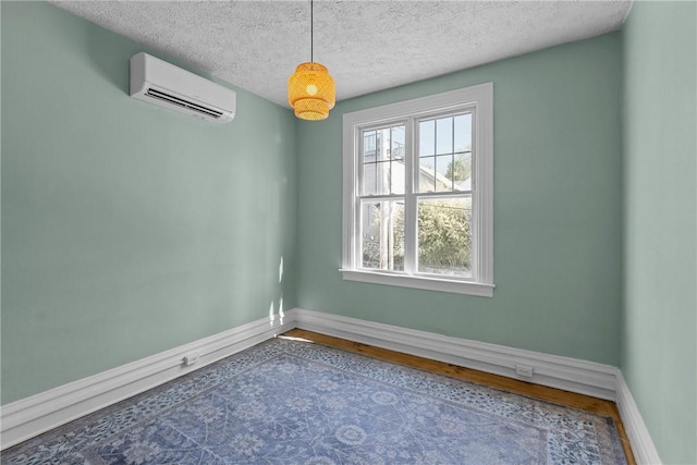 unfurnished room featuring baseboards, a textured ceiling, and a wall mounted AC