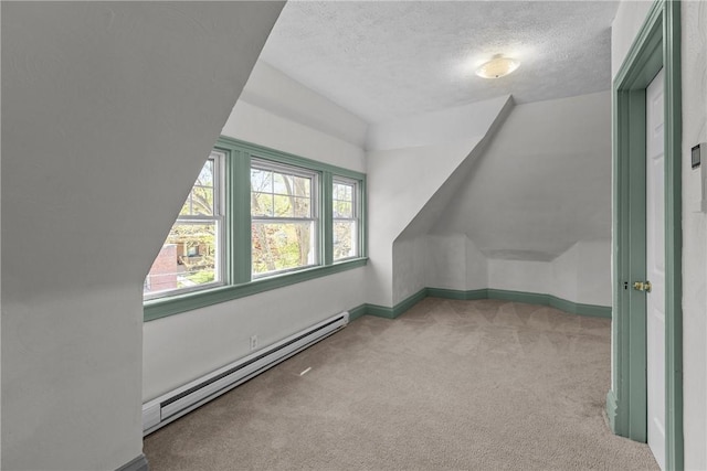 additional living space with baseboards, a baseboard radiator, a textured ceiling, and carpet flooring