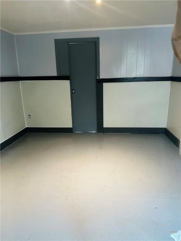 spare room with crown molding, baseboards, and finished concrete floors
