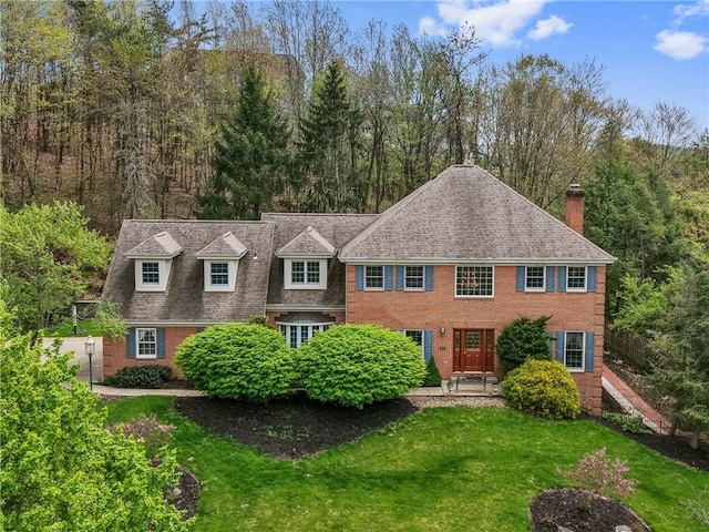 1641 Blackburn Heights Dr, Franklin Park, PA 15143 - view of front facade with roof with shingles, brick siding, a front yard, a chimney, and a forest view