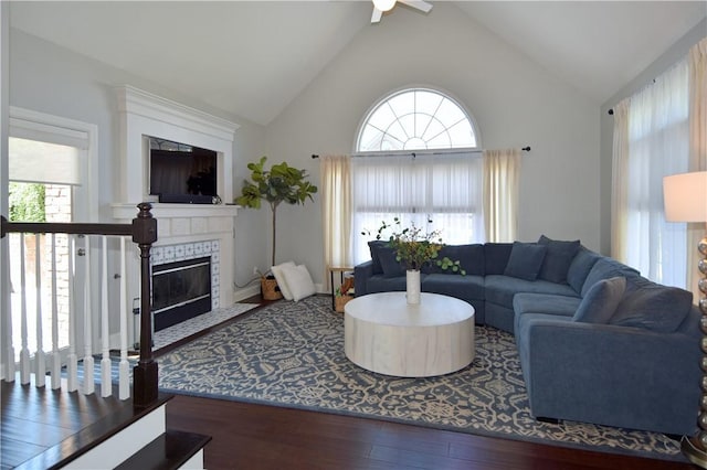 living area with a fireplace with flush hearth, a ceiling fan, wood finished floors, and a wealth of natural light