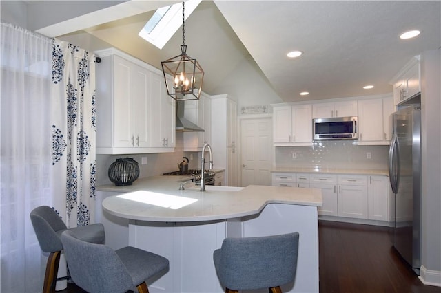 kitchen with a peninsula, white cabinetry, appliances with stainless steel finishes, and light countertops