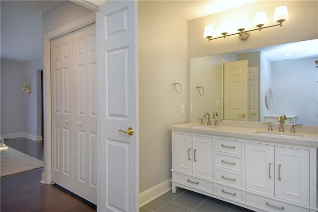 bathroom with baseboards, a sink, and double vanity