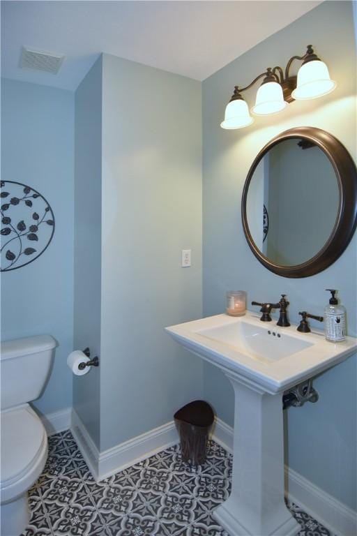 half bath with visible vents, baseboards, tile patterned floors, and toilet