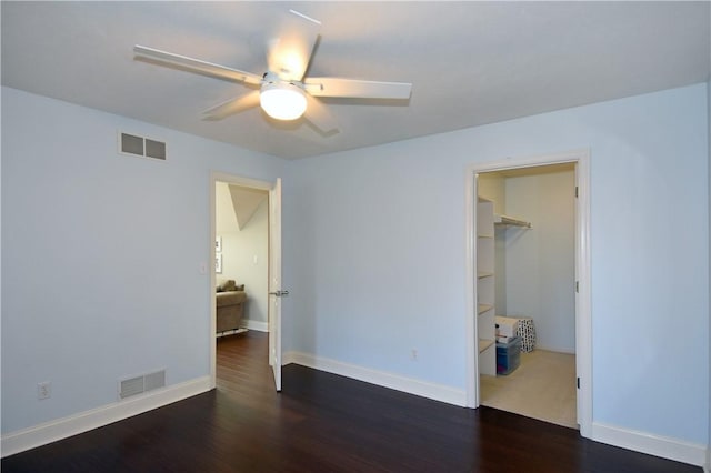 unfurnished bedroom featuring baseboards, visible vents, wood finished floors, and a spacious closet