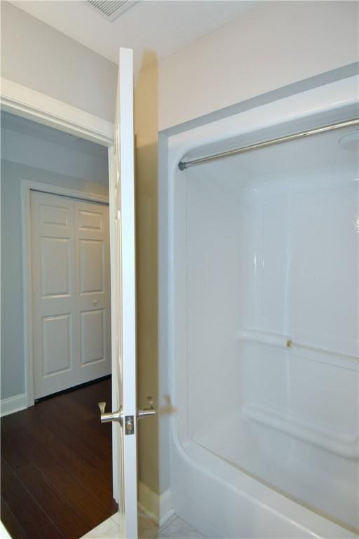 bathroom featuring baseboards, walk in shower, wood finished floors, and visible vents