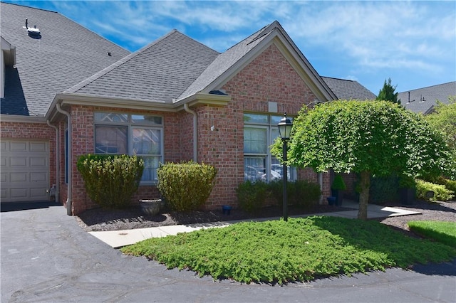 view of front of property with a shingled roof, an attached garage, driveway, and brick siding