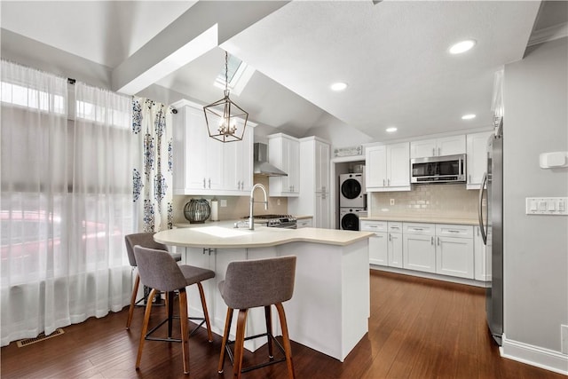 1501 Appleridge Ct, Adams Twp, PA 15044 - kitchen featuring appliances with stainless steel finishes, stacked washing machine and dryer, vaulted ceiling, a peninsula, and a sink