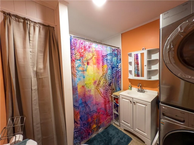 full bath featuring crown molding, vanity, stacked washer / drying machine, and curtained shower
