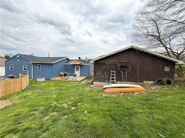 rear view of house with fence, an outbuilding, a yard, and a patio