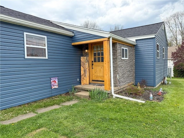doorway to property with a lawn and a shingled roof