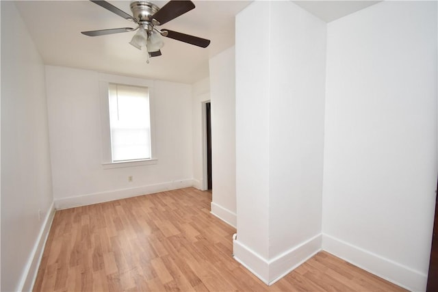 spare room with baseboards, ceiling fan, and light wood-style floors