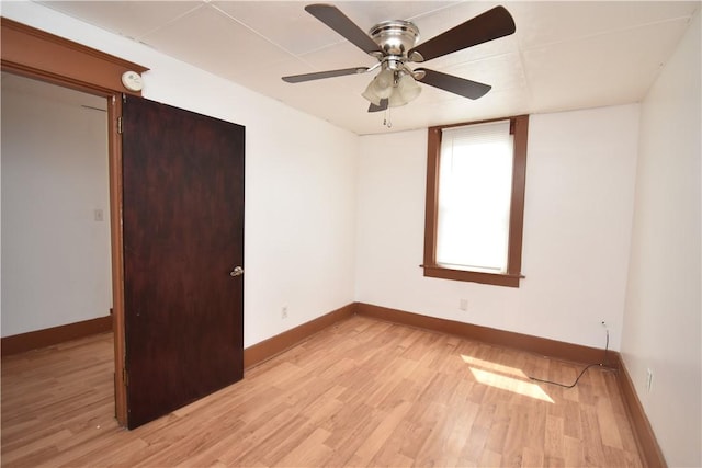 unfurnished room with a ceiling fan, baseboards, and light wood-type flooring