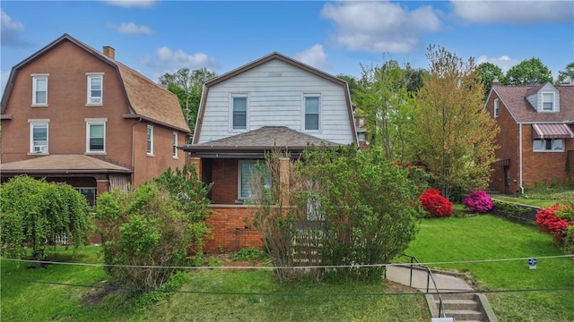 view of front of property featuring brick siding, a gambrel roof, a front lawn, and a chimney