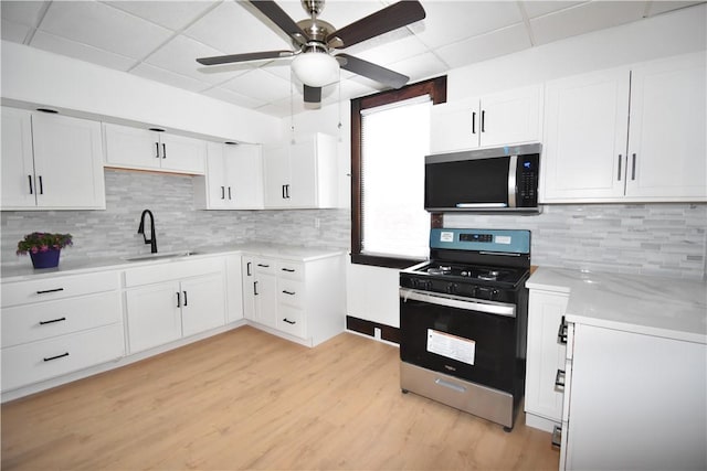 kitchen with white cabinets, appliances with stainless steel finishes, a sink, a ceiling fan, and a drop ceiling
