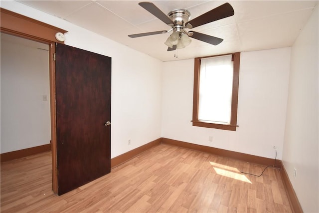 empty room with baseboards, ceiling fan, and light wood-type flooring