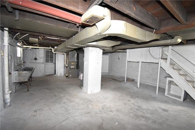 unfinished below grade area with heating unit and brick wall