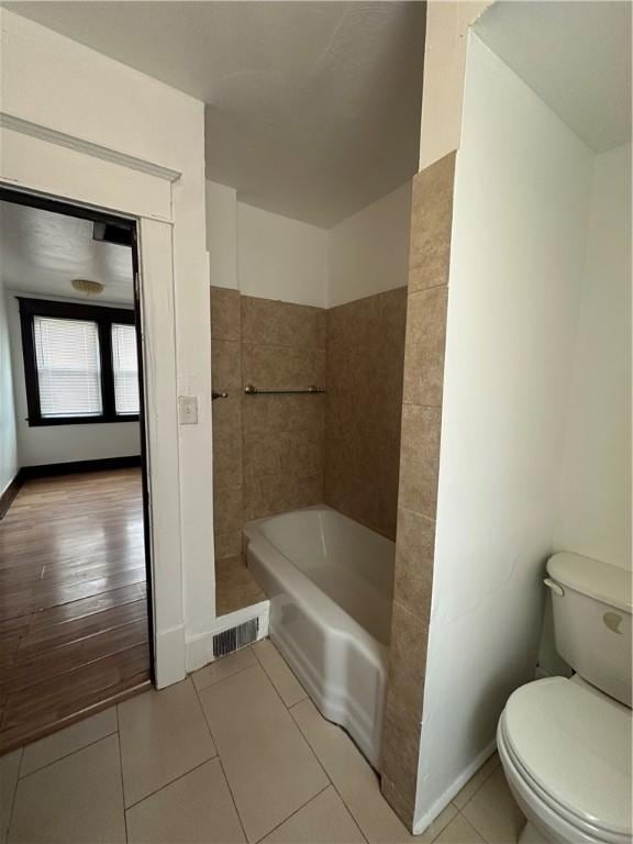 bathroom with walk in shower, toilet, tile patterned floors, a tub, and baseboards