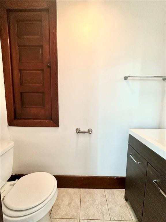 bathroom with toilet, baseboards, tile patterned floors, and vanity