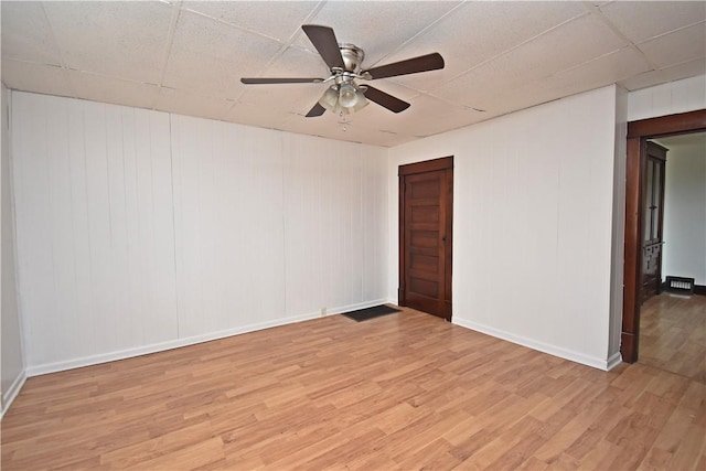 spare room with a ceiling fan, baseboards, a paneled ceiling, and light wood finished floors