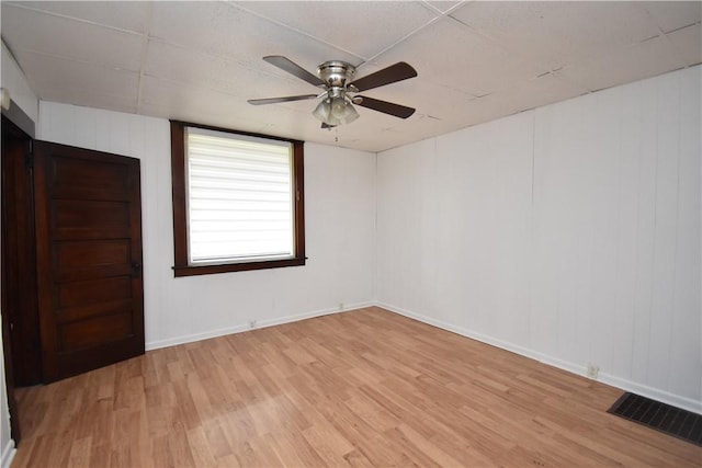 empty room with baseboards, ceiling fan, light wood finished floors, and visible vents