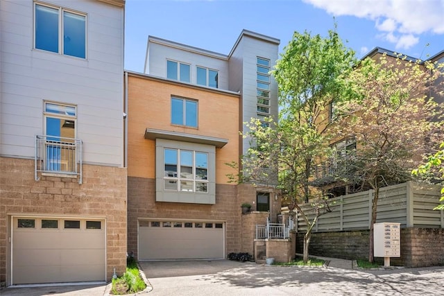 townhome / multi-family property featuring an attached garage, concrete driveway, and brick siding