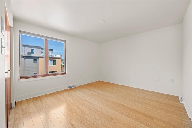 unfurnished room with visible vents, baseboards, and wood finished floors