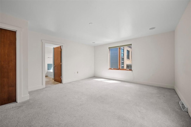 unfurnished room featuring baseboards, visible vents, and light colored carpet
