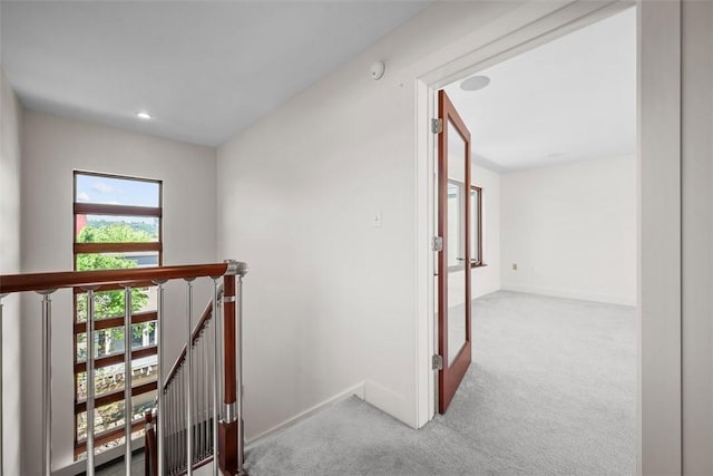 corridor with carpet floors, recessed lighting, baseboards, and an upstairs landing