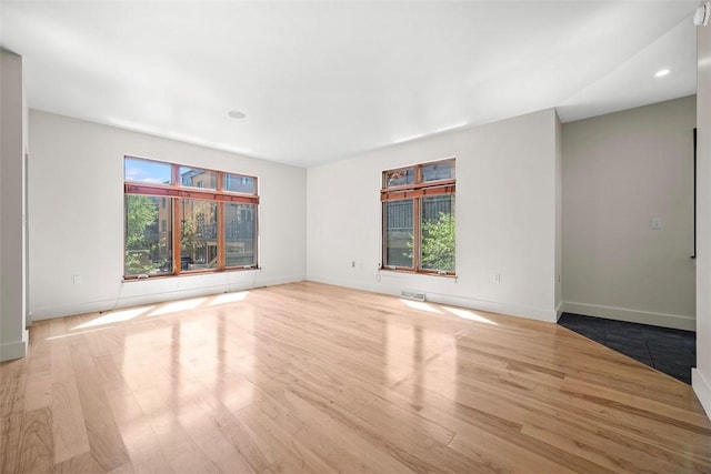 empty room with baseboards, recessed lighting, and wood finished floors