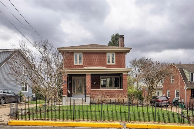 american foursquare style home with a porch, a fenced front yard, a chimney, brick siding, and a front lawn
