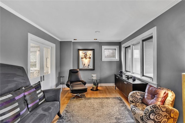 living area featuring crown molding, baseboards, plenty of natural light, and light wood-type flooring