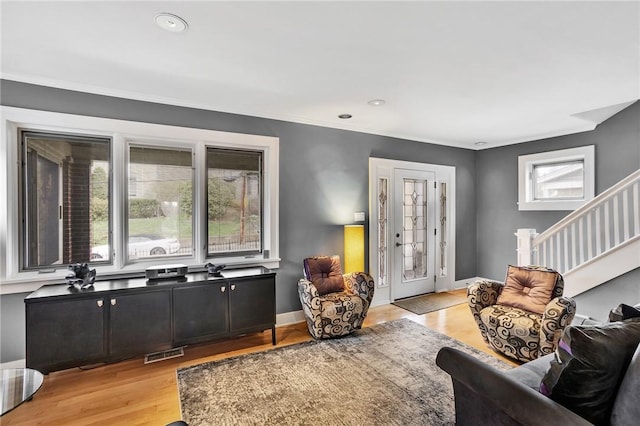 living area featuring crown molding, light wood-style flooring, recessed lighting, visible vents, and stairway