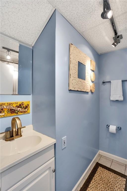 bathroom featuring tile patterned floors, baseboards, rail lighting, and vanity