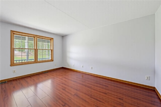empty room with baseboards, visible vents, and wood finished floors