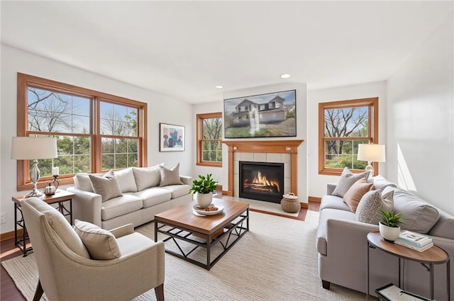 living room featuring light wood-style floors, recessed lighting, baseboards, and a tiled fireplace