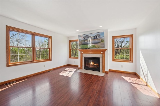 unfurnished living room featuring baseboards, visible vents, a tiled fireplace, and a healthy amount of sunlight