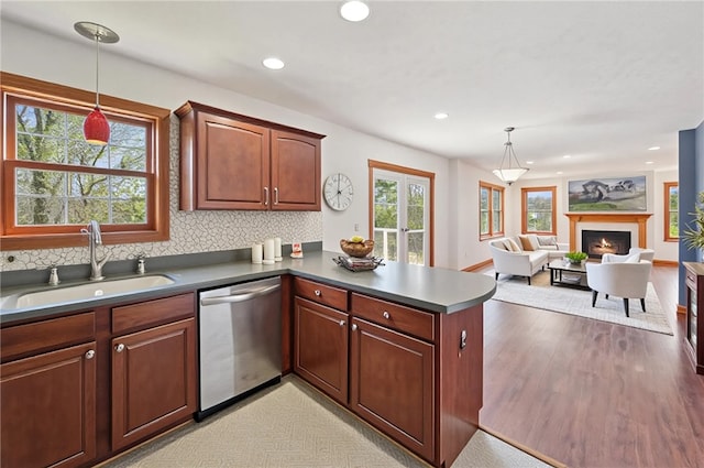 kitchen featuring a peninsula, dishwasher, recessed lighting, a sink, and backsplash