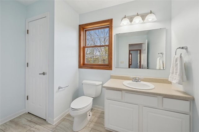 bathroom with tile patterned flooring, baseboards, toilet, and vanity