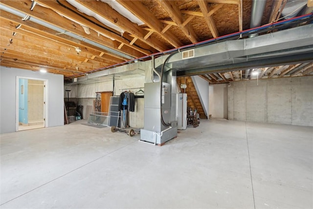 unfinished below grade area featuring visible vents, heating unit, water heater, and stairs
