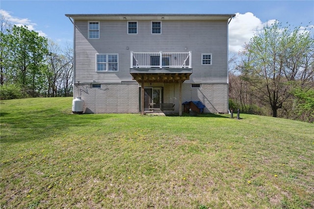 back of house featuring a balcony, a yard, and brick siding