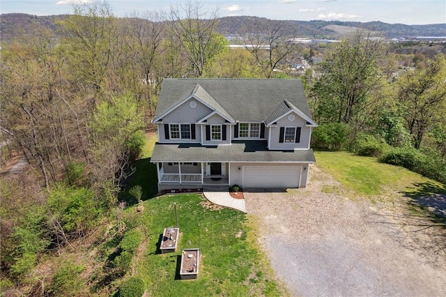 view of front of property featuring a porch, a garage, driveway, and a front lawn