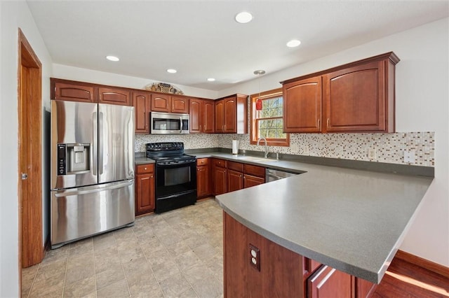 kitchen with appliances with stainless steel finishes, tasteful backsplash, dark countertops, a sink, and a peninsula