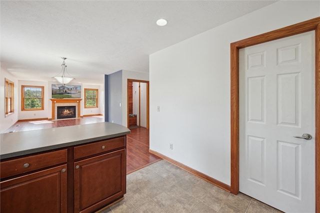 kitchen featuring decorative light fixtures, baseboards, open floor plan, and a tile fireplace
