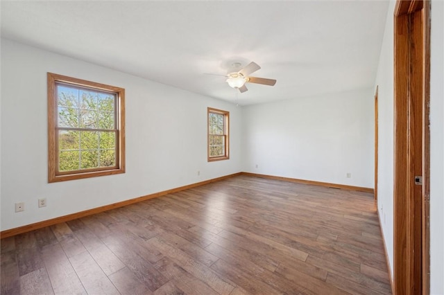 empty room with wood-type flooring, a ceiling fan, and baseboards