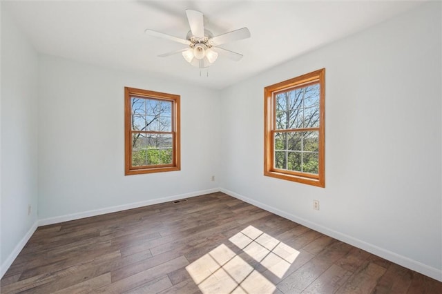 spare room featuring a healthy amount of sunlight, baseboards, and hardwood / wood-style floors