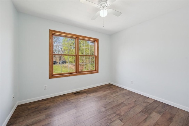 empty room featuring baseboards, visible vents, and dark wood-style floors
